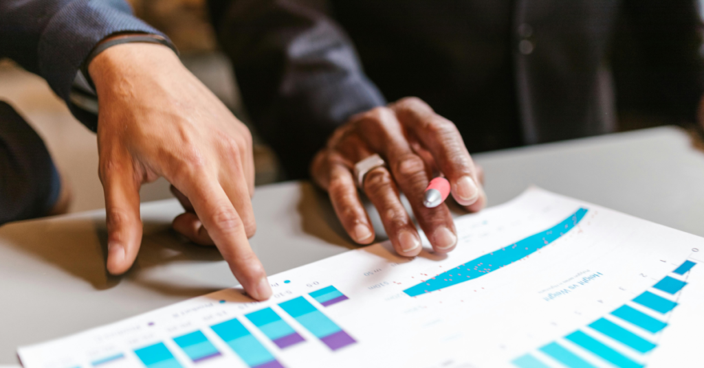 Two hands pointing at sheets of data in various graph forms