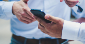 Two people in blue shirts looking at a mobile phone