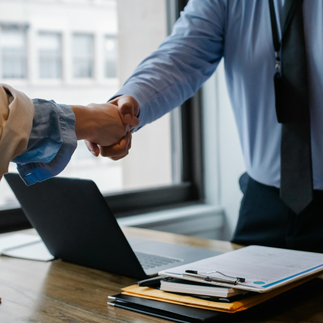 Man and woman shake hand across a table